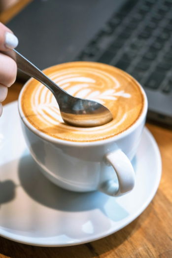 Spoon mixing beautiful latte art in a cup.